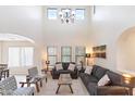 Bright living room with high ceilings, gray sofas, and a large chandelier at 8147 W Hilton Ave, Phoenix, AZ 85043