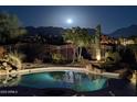 Backyard pool with a view of the mountains under a full moon at night at 19771 N 84Th Way, Scottsdale, AZ 85255