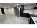 Open-concept kitchen showcases stainless steel refrigerator, black cabinetry, white countertops, and light wood-look floors at 1983 E Don Carlos Ave, Tempe, AZ 85281