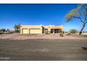 Tan stucco home with three-car garage and desert landscaping at 20040 W Hunter Dr, Wittmann, AZ 85361