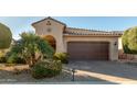 Tan two-story house with a brown garage door and palm trees in front at 21720 N 265Th Dr, Buckeye, AZ 85396