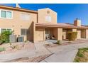 Tan two-story stucco home with front patio, two chairs, and landscaping at 3511 E Baseline Rd # 1206, Phoenix, AZ 85042