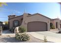 Front view of a tan house with a brown garage door and desert landscaping at 9219 S 185Th Ave, Goodyear, AZ 85338