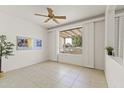 Neutral bedroom with tiled floor, plantation shutters, ceiling fan, and a view to the outdoors at 23114 N 146Th Dr, Sun City West, AZ 85375