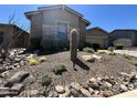 Lush front yard showcasing desert landscaping, including a large cactus, rocks, and other vegetation with stone accents at 23448 N 76Th Pl, Scottsdale, AZ 85255