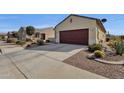 House exterior showcasing a red garage door and drought-tolerant landscaping at 42157 W Cribbage Rd, Maricopa, AZ 85138