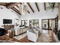 Bright living room with hardwood-look tile, exposed beams, and access to outdoor living spaces at 8119 E Foothills Dr, Scottsdale, AZ 85255