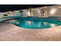 Inviting kidney-shaped pool with waterfalls and string lights at night at 16846 W Hilton Ave, Goodyear, AZ 85338