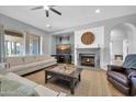 Bright living room with a fireplace, neutral colors, ceiling fan, and a cozy seating arrangement at 22717 W Sierra Ridge Way, Wittmann, AZ 85361