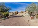 Sprawling single-story home with a lushly landscaped front yard and a brick driveway at 3254 N Ladera Cir, Mesa, AZ 85207