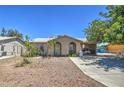 Tan single story home with a spacious yard and mature tree at 7201 W Alvarado Rd, Phoenix, AZ 85035