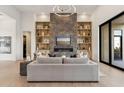 Modern living room with fireplace, shelving, light wood floors and gray couch centered on neutral rug at 15609 E Palatial Estates Dr, Fountain Hills, AZ 85268
