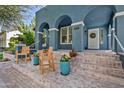 Blue house's spacious brick front porch features wooden chairs and colorful potted plants at 3021 E Agritopia N Loop, Gilbert, AZ 85296