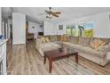 Living room with L-shaped sofa, wood-look floors, and a ceiling fan at 49201 N 24Th Ave, New River, AZ 85087