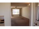 Living room with carpet, large window and access to other rooms at 9714 W Edward Dr, Sun City, AZ 85351