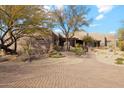 Welcoming desert home with a beautiful, landscaped front yard and brick paver driveway leading to the entrance at 8220 E Cavalry Dr, Scottsdale, AZ 85266