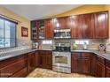 Well-equipped kitchen featuring dark wood cabinets, granite countertops, and stainless steel appliances at 11259 W Harrison St, Avondale, AZ 85323