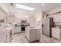 Well-lit kitchen featuring a skylight, central island, stainless steel appliances, and ample cabinet space at 22801 N Las Vegas Dr, Sun City West, AZ 85375