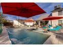 Inviting pool area with lounge seating, red umbrellas, and lush landscaping at 4453 E Whitney Ln, Phoenix, AZ 85032