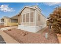 Tan mobile home with a view of the street and neighboring homes at 111 S Greenfield Rd # 827, Mesa, AZ 85206