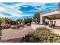 Beautifully landscaped backyard with desert plants, a covered patio, and views of palm trees and blue sky at 17061 W Peregrine Ln, Surprise, AZ 85387