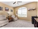 Cozy living room featuring plush chairs, a ceiling fan, and a large arched window with blinds at 24338 W Albeniz Pl, Buckeye, AZ 85326