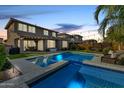 Evening view of a private backyard pool with lighting, seating area, and a spa at 3320 E Tina Dr, Phoenix, AZ 85050