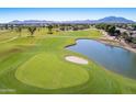 Aerial view of the golf course showcasing lush greenery, a serene pond, and picturesque mountain views at 4439 E Ficus Way, Gilbert, AZ 85298