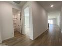 Bright hallway with wood-look floors and white walls leading to bedrooms and bathrooms at 9526 W Luxton Ln, Tolleson, AZ 85353