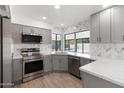 Modern kitchen featuring gray cabinets, quartz countertops, and stainless steel appliances at 9832 W Oraibi Dr, Peoria, AZ 85382