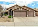 Inviting home exterior with a three-car garage, desert landscaping, and a cozy arched entrance at 10971 W Tonopah Dr, Peoria, AZ 85373