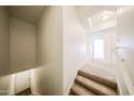 Carpeted stairs leading down to a white door and tile flooring, with an archway in the background at 14250 W Wigwam Blvd # 2822, Litchfield Park, AZ 85340