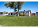 Inviting single-story home boasts mature trees, a lush lawn, and a welcoming facade at 2527 N 69Th Pl, Scottsdale, AZ 85257