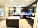 Modern kitchen with dark cabinets, granite countertops, and stainless steel appliances at 3937 S 79Th Ln, Phoenix, AZ 85043