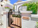 Charming wrought iron gate with lush landscaping and decorative planters and house number at 10120 E Topaz Dr, Scottsdale, AZ 85258
