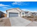 Inviting single-story home with a gray stucco exterior, gray garage door, desert landscaping, and concrete driveway at 2530 W Sable Ave, Apache Junction, AZ 85120