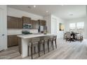 Open concept kitchen with island seating, dining area, and wood cabinets at 2811 N 212Th Dr, Buckeye, AZ 85396