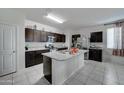 Open kitchen with a large island, stainless steel appliances, and dark wood cabinets at 30263 W Pinchot Ave, Buckeye, AZ 85396