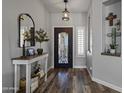 Inviting foyer with wood floors, decorative mirror, and a black metal door and light fixture at 8171 W Beaubien Dr, Peoria, AZ 85382