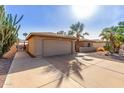 Home's exterior features a two-car garage, desert landscaping, and a well-maintained driveway at 9725 E Navajo Pl, Sun Lakes, AZ 85248