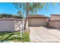 Beige stucco home featuring a two-car garage, and a well-maintained yard with mature trees and bushes at 11129 N 109Th St, Scottsdale, AZ 85259