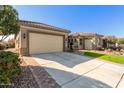 Tan house with a two-car garage and a manicured lawn at 7815 W Cinder Brook Way, Florence, AZ 85132