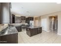 Contemporary kitchen with a central island, stainless steel appliances, dark wood cabinets, and tiled flooring at 1203 E Judi St, Casa Grande, AZ 85122