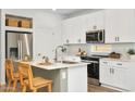 Modern kitchen with white cabinets, island, and stainless steel appliances at 18094 W Sand Hills Dr, Surprise, AZ 85387