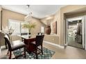 Glass-topped dining table with four chairs, modern chandelier, and adjacent room view at 3236 E Chandler Blvd # 2053, Phoenix, AZ 85048