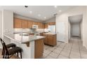 Well-lit kitchen featuring tile flooring, wood cabinets, white appliances and an island with space for seating at 19850 N 110Th Ln, Peoria, AZ 85373