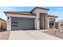 Modern single-story home featuring a gray garage door with windows, stone accents and desert landscaping at 564 E Aurora Dr, San Tan Valley, AZ 85140