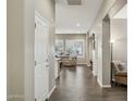 Inviting hallway with wood floors and neutral walls leading to a living area with bright windows at 16954 W Palm Ln, Goodyear, AZ 85395