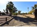 Long, gravel driveway lined with a wooden fence and mature trees leads to the house, providing ample parking space at 7043 E Ann Way, Scottsdale, AZ 85254