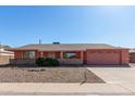 Single story home with peach stucco exterior, two-car garage, and desert landscaping at 11029 W Meade Dr, Sun City, AZ 85351